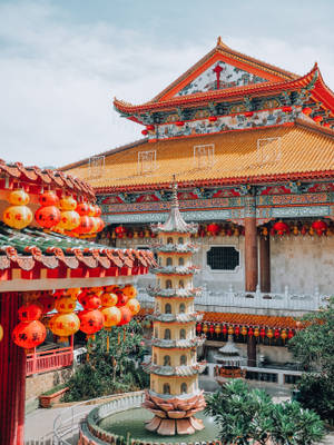 色彩繽紛的中國寺廟庭院，有紅色燈籠和中央的寶塔噴泉。 — 慶祝 壁紙