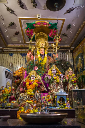 寺廟神龕中裝飾著鮮花的金色印度教神像。 — Maa Durga 壁紙
