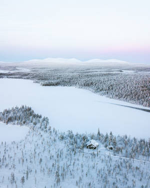雪林暮色中，遠處有山巒的孤獨小屋。 — 冬季風景 壁紙