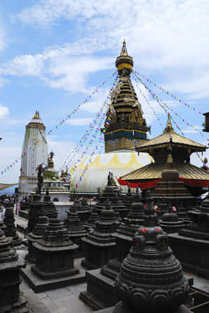 金色佛教佛塔，被石佛塔和經幡環繞，背景是藍天。 — 靈性美學 壁紙
