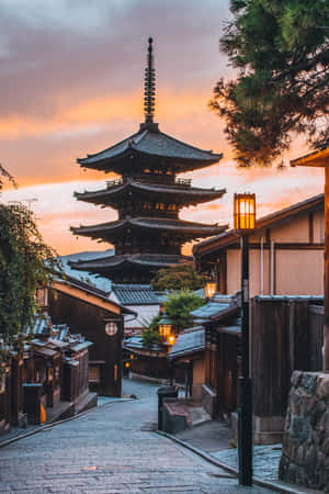 日落時分的傳統日本寺廟塔樓，石頭街道旁閃耀的燈籠。 — 日本 壁紙