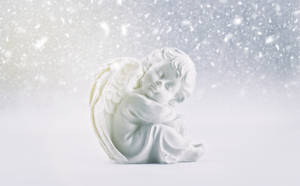 一座白色大理石天使雕像在飄雪下蜷縮入睡。 — 冬季美學 壁紙