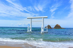 白色鳥居立於海中，背景有岩石島嶼，天空湛藍 — 日式海浪 壁紙