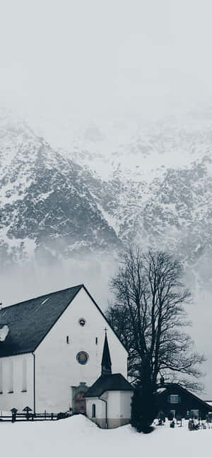 雪中的小白教堂，背景有山。 — Xiaomi 壁紙