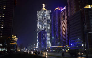 夜晚的城市景觀， featuring 一座頂部有金色雕像的發光摩天大樓。 — 南韓 壁紙