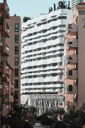 藍天下陶土色公寓之間的現代白色波浪形建築 — 摩納哥 壁紙