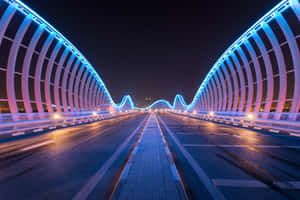 一座現代照明橋樑在夜晚，帶有藍色霓虹燈和濕潤的路面。 — 夜空 壁紙