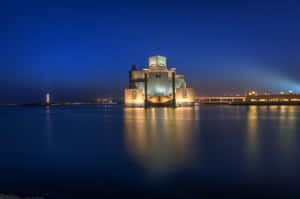 夜晚發光的現代博物館，帶有水影和城市燈光。 — 桌面 壁紙