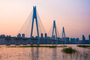 日落時河流上的現代斜張橋與城市天際線 — 塔橋 壁紙