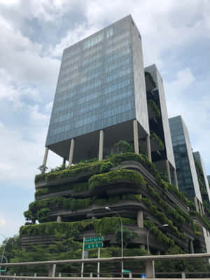 陰天下，高聳的玻璃建築帶有綠色露台。 — iPad Pro M4 壁紙