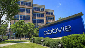 AbbVie公司標誌，位於現代辦公大樓前，周圍有綠色景觀。 — 高清 壁紙