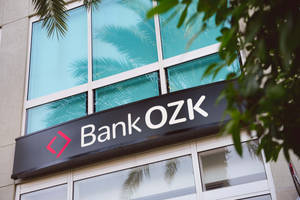 現代建築上的 Bank OZK 招牌，配有棕櫚樹和玻璃窗。 — 簡約 壁紙
