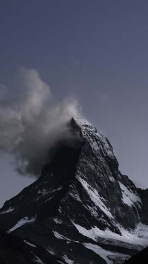 一座白雪覆蓋的山峰，雲霧在山頂周圍旋轉。 — 岩石 壁紙