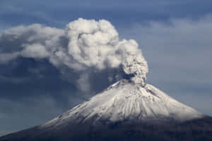 白雪覆蓋的火山噴發，厚厚的火山灰雲在暴風雨的天空下。 — 雪景 GIF 壁紙