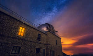 石造天文台，發光窗戶，星空和夕陽雲彩下。 — 宇宙 壁紙