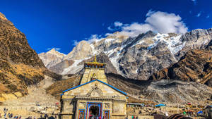 一座色彩繽紛的寺廟，坐落在山谷中，背景是白雪覆蓋的山峰。 — 金廟 壁紙