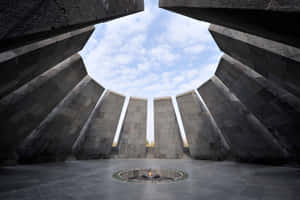 一座石造紀念碑，中央有永恆火焰，天空多雲。 — 建築 壁紙