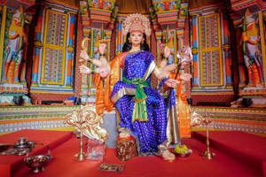一座色彩繽紛的印度教女神雕像，坐在裝飾寺廟內的紅色平台上。 — Maa Durga 壁紙