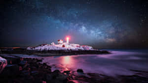 被雪覆蓋的燈塔在繁星點點的夜空下發出紅光，銀河在平靜的海洋上方。 — 暮光 壁紙