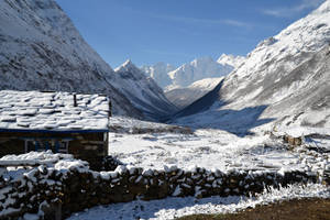 雪覆蓋的石屋在山谷中，聳立著山峰 — 茶園 壁紙