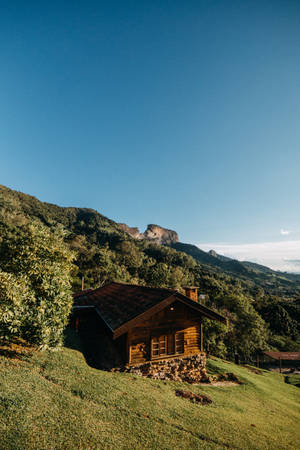 草地上的質樸木屋，青山和藍天 — 丘陵景觀 壁紙