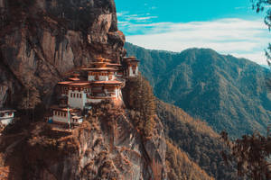 寺院棲息在懸崖邊緣，俯瞰森林山谷 — 不丹 壁紙
