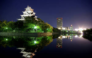 夜晚平靜水面上倒映的燈光城堡和城市天際線。 — 東京鐵塔 壁紙
