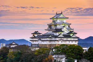 夕陽下的傳統日本城堡，背景有山和樹木。 — MacBook Pro M3 壁紙