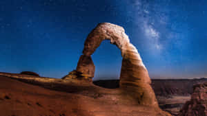 在繁星點點的夜空下發光的石拱，銀河清晰可見。 — 月亮與星星 壁紙