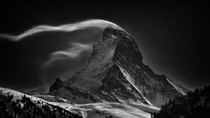 星空下白雪覆蓋的山峰與流動的雲層 — 冬季風景 壁紙