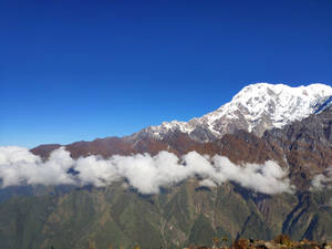 雪山峰在雲層之上聳立於藍天 — 山坡 壁紙