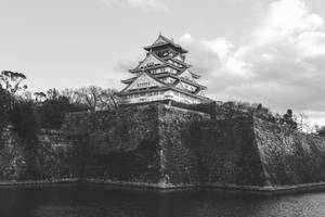 一座歷史悠久的日本城堡，在陰天之下擁有石牆和護城河。 — 京都 壁紙