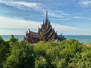 一座木製寺廟被綠樹環繞，背景是海洋和天空。 — 海洋 壁紙