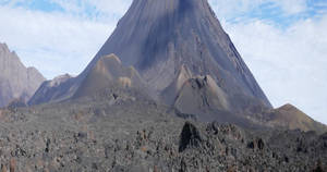 一座大型火山山脈，擁有深色山坡和多岩石的地形，天空多雲。 — 山脈 壁紙