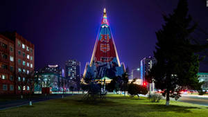 夜間城市環境中，一座明亮照明的金字塔建築帶有政治壁畫。 — 夜景城市 壁紙