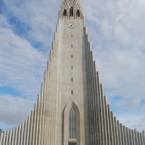 多雲天空下的幾何尖頂現代混凝土教堂。 — 手機 壁紙