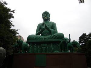 公園環境中，被大象環繞的大型綠色佛像。 — 日式審美桌面 壁紙