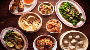 木桌上擺放著包括餃子、春捲和蔬菜在內的中式菜餚盤子。 — 高對比 壁紙