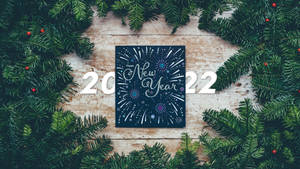 木質表面上以常青樹枝框住的2022年新年賀卡。 — 新年快樂 2020 壁紙