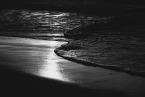 海浪在夜間沖刷濕沙，帶有明亮倒影。 — 海灘 壁紙
