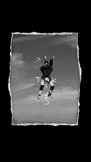 一個人在陰天背景下舉起雙臂跳躍，帶有手寫文字。 — 崔維斯·史考特 GIF 壁紙