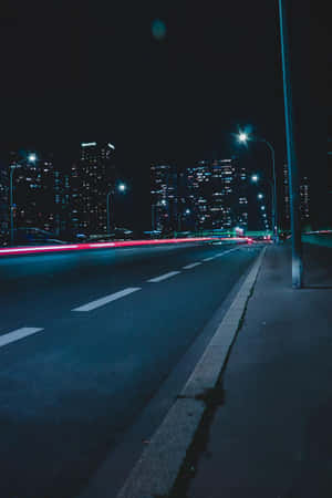 夜間城市高速公路，帶有紅色汽車燈光條紋和明亮的建築物。 — 晚安 壁紙