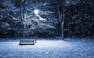 夜間，積雪覆蓋公園長椅，下方街燈閃爍。 — 冬季風景 壁紙