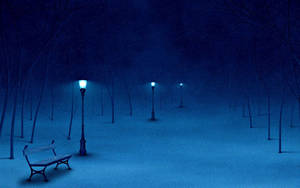 夜晚的雪地公園，長椅和發光路燈在飄雪下。 — 夜晚 壁紙