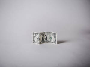 一張折疊的一美元鈔票直立於灰色背景上。 — 金錢 壁紙