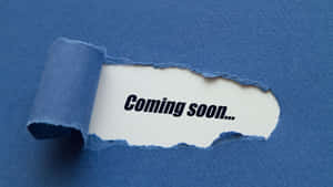 撕破的藍色紙張露出「Coming soon...」文字。 — Studio Display 壁紙