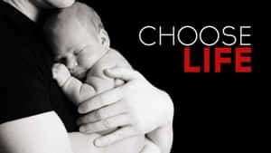 一位成人抱著熟睡的嬰兒，上面有紅色文字「CHOOSE LIFE」。 — 奇妙人生 壁紙