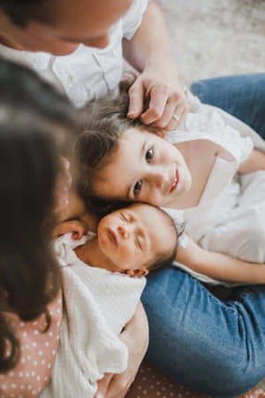 一位母親、父親和兩個孩子在舒適的室內環境中擁抱在一起。 — 小莫娜 壁紙