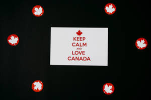 白色卡片，紅色文字寫著 Keep Calm and Love Canada，周圍是紅色楓葉貼紙。 — 加拿大 iPhone 壁紙