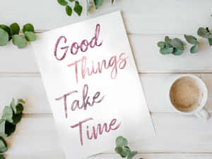 卡片寫著 Good Things Take Time，搭配咖啡和綠色植物在木頭上。 — 玫瑰金美學 壁紙